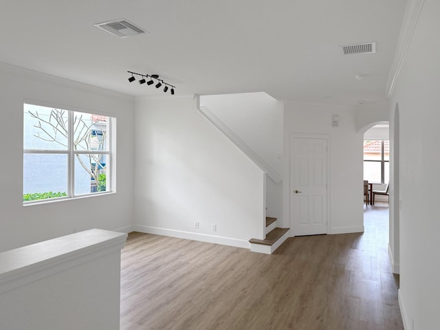 interior space with stairs, ornamental molding, arched walkways, and visible vents