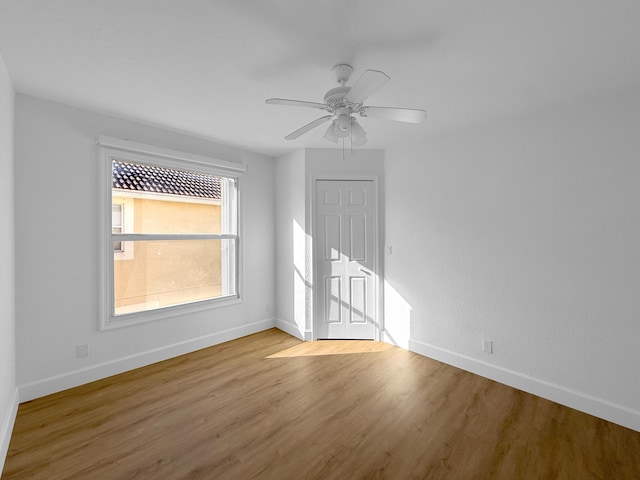 unfurnished room with light wood-style floors, baseboards, and a ceiling fan