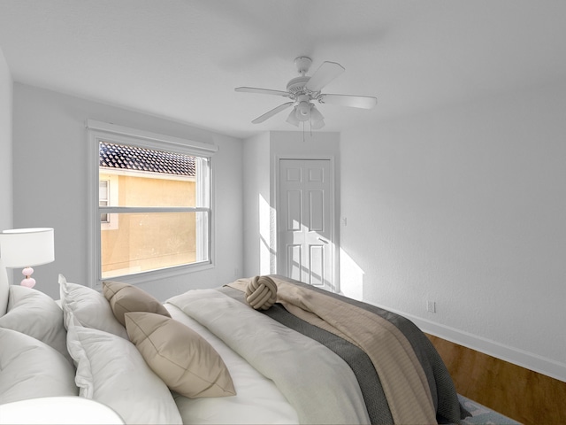 bedroom with a ceiling fan, baseboards, and wood finished floors