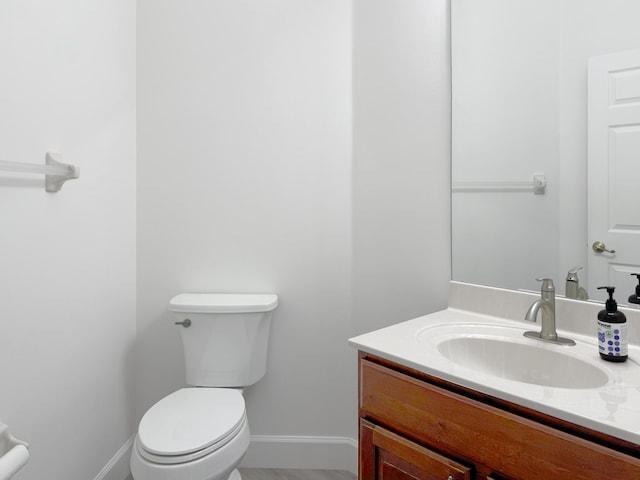 bathroom with baseboards, vanity, and toilet