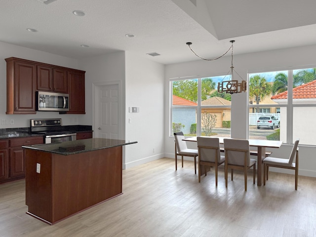 kitchen featuring stainless steel appliances, a wealth of natural light, a kitchen island, and visible vents