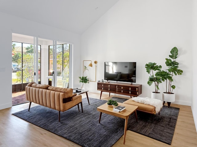 living room with baseboards, high vaulted ceiling, and light wood-style floors