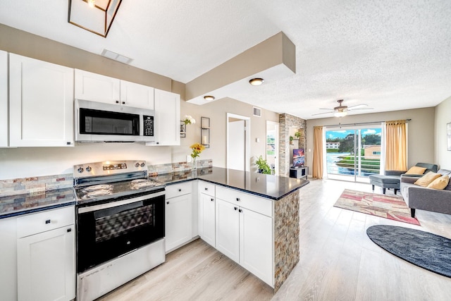 kitchen featuring light wood-type flooring, dark countertops, open floor plan, stainless steel appliances, and a peninsula