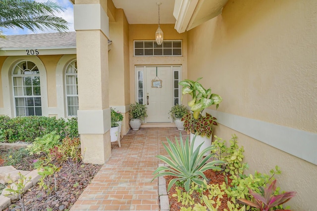 property entrance featuring stucco siding and a shingled roof