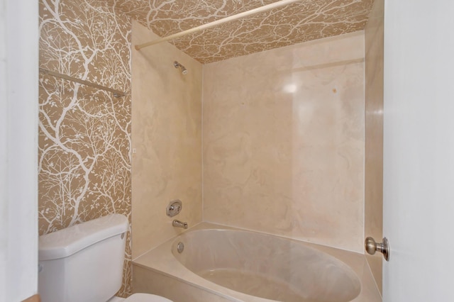 bathroom with bathtub / shower combination, toilet, and wallpapered walls