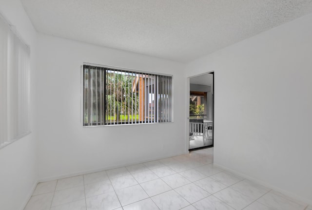 spare room with tile patterned floors, baseboards, and a textured ceiling