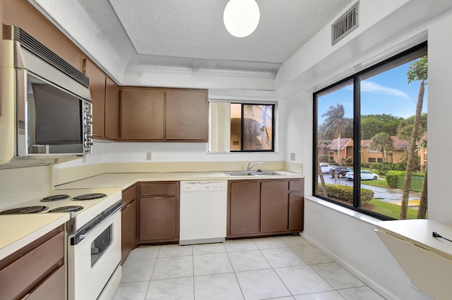 kitchen featuring white appliances, visible vents, a sink, light countertops, and a textured ceiling