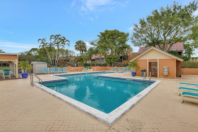 pool featuring an outbuilding, a patio, and fence