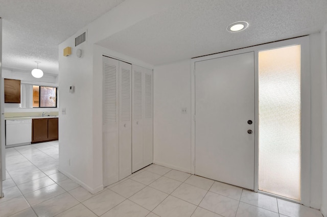 interior space with light tile patterned floors, baseboards, visible vents, and a textured ceiling