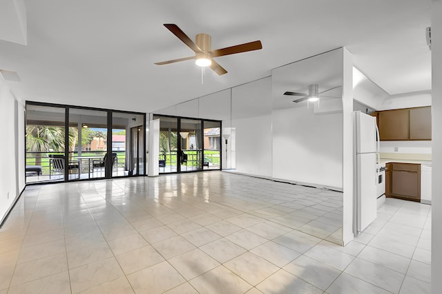 unfurnished room featuring ceiling fan, expansive windows, and light tile patterned flooring