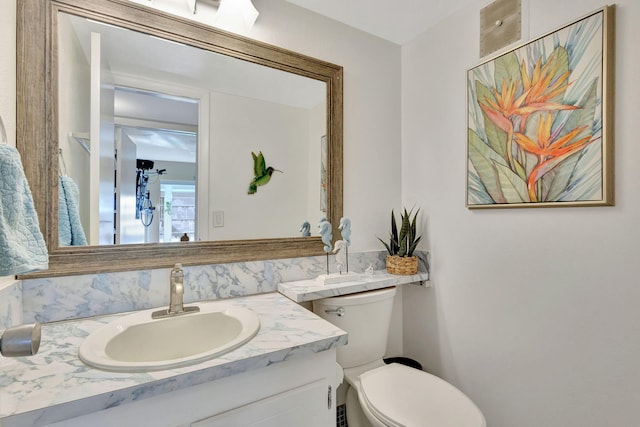 half bathroom with decorative backsplash, vanity, and toilet