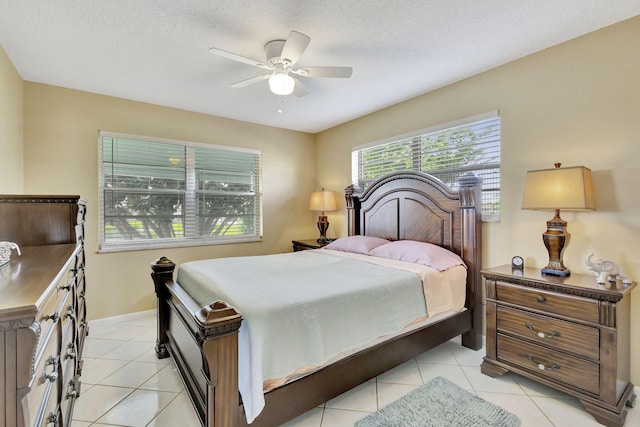 bedroom with light tile patterned flooring, ceiling fan, a textured ceiling, and baseboards