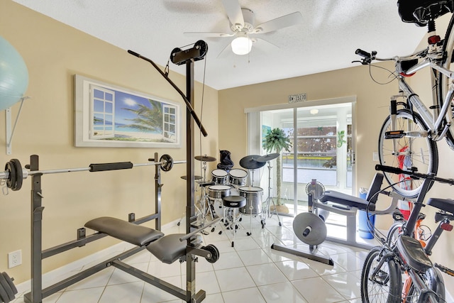 exercise room featuring light tile patterned floors, a ceiling fan, and a textured ceiling