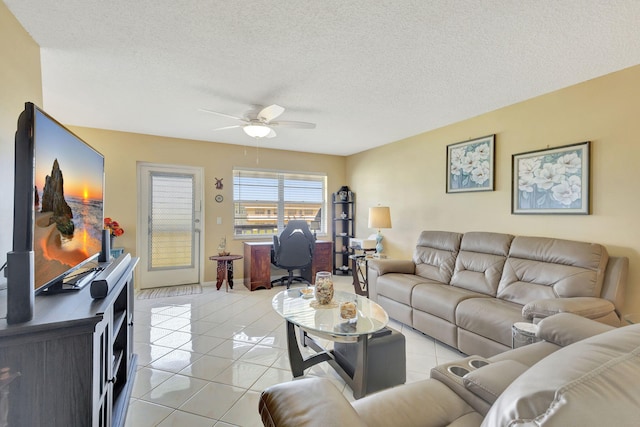 living area with a ceiling fan, light tile patterned flooring, and a textured ceiling