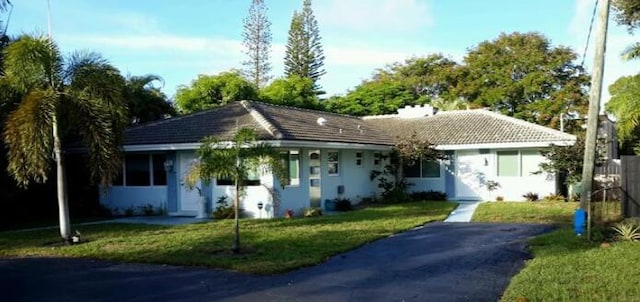 ranch-style home with a tiled roof, a front lawn, and stucco siding