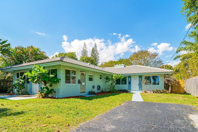 single story home featuring a tile roof, fence, a front lawn, and stucco siding