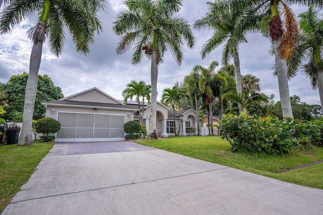 single story home with a garage, driveway, a front yard, and stucco siding