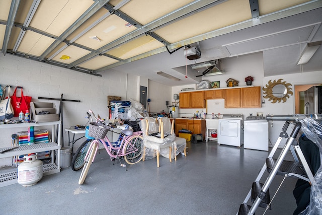 garage with concrete block wall, electric panel, a garage door opener, and independent washer and dryer