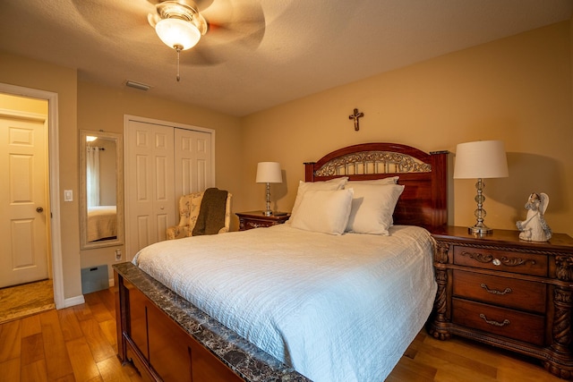 bedroom featuring light wood finished floors, a closet, visible vents, a ceiling fan, and a textured ceiling