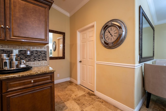 kitchen featuring ornamental molding, stone counters, backsplash, and baseboards