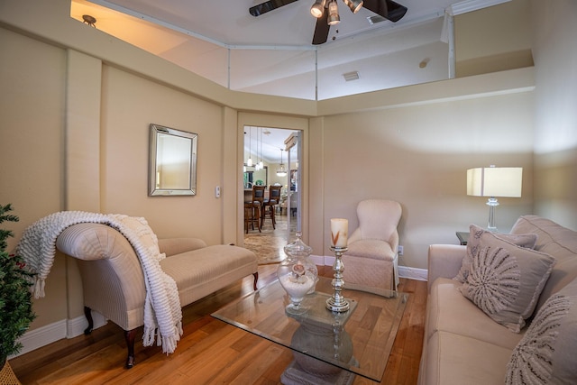 living room with wood finished floors, visible vents, a ceiling fan, vaulted ceiling, and baseboards