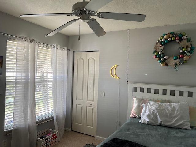 bedroom featuring a textured ceiling, ceiling fan, and light tile patterned flooring