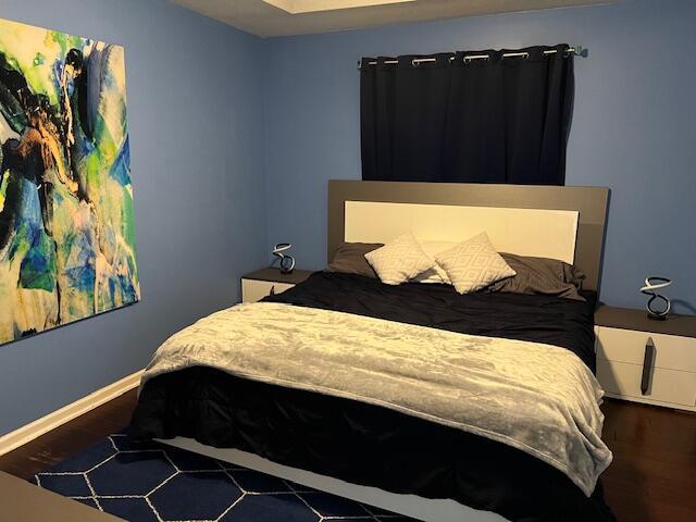 bedroom with baseboards and wood finished floors