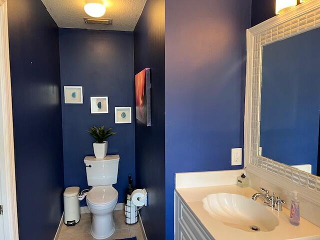 bathroom with visible vents, toilet, vanity, a textured ceiling, and tile patterned flooring