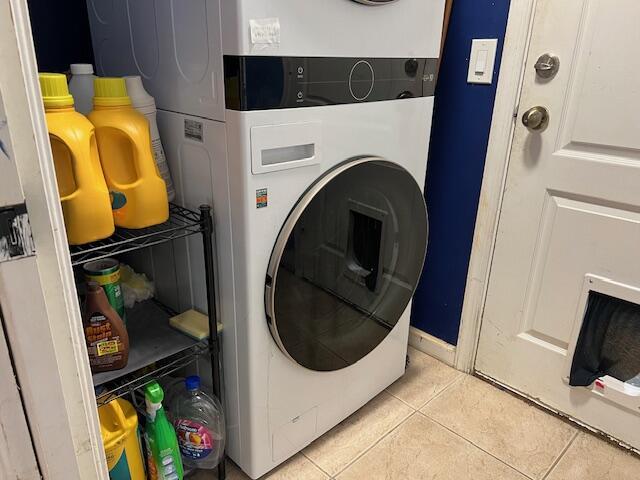 laundry room with stacked washer / drying machine, laundry area, and light tile patterned floors