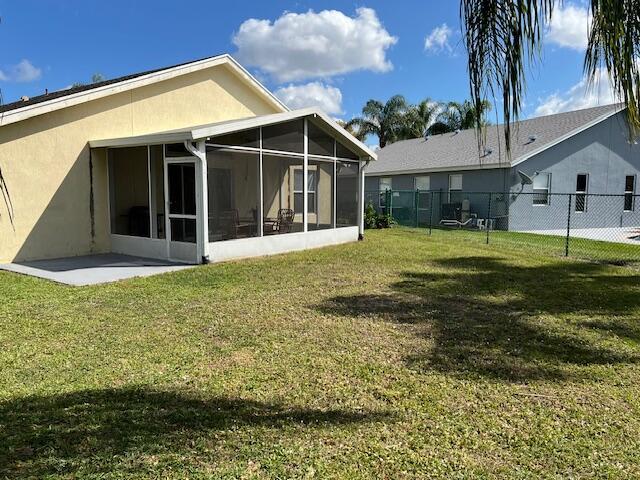 back of property with stucco siding, a lawn, and fence