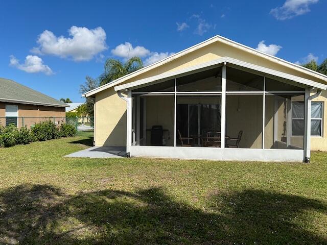 back of house featuring a sunroom and a lawn