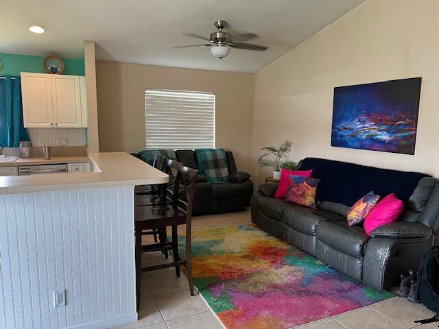 living area featuring light tile patterned floors, vaulted ceiling, and a ceiling fan