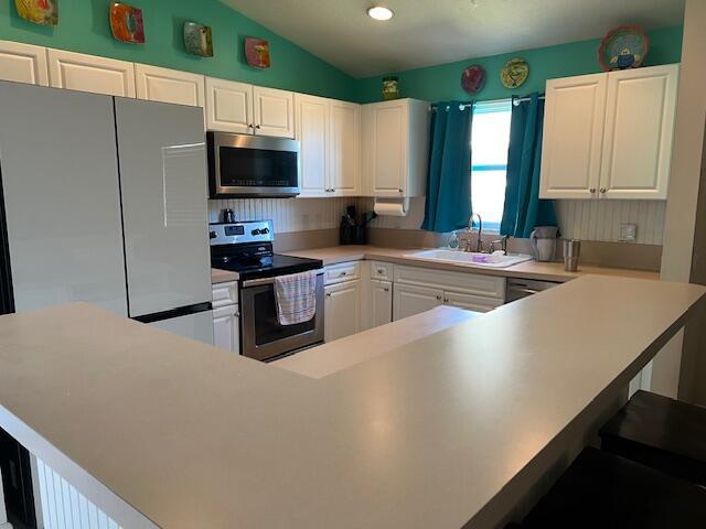 kitchen featuring white cabinetry, stainless steel appliances, a sink, and light countertops