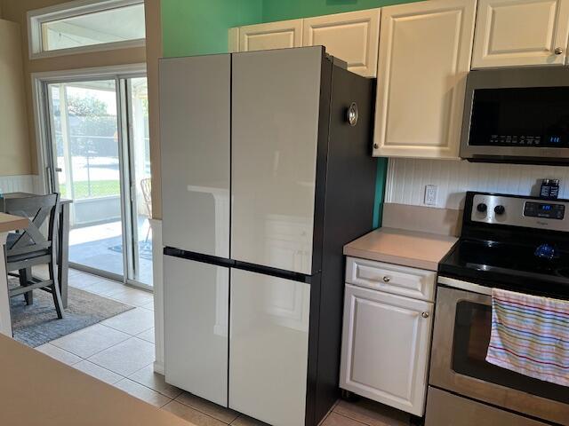 kitchen featuring white cabinets, appliances with stainless steel finishes, light countertops, and light tile patterned flooring