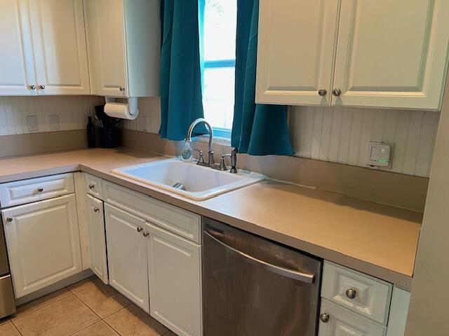 kitchen featuring white cabinets, light countertops, and dishwasher