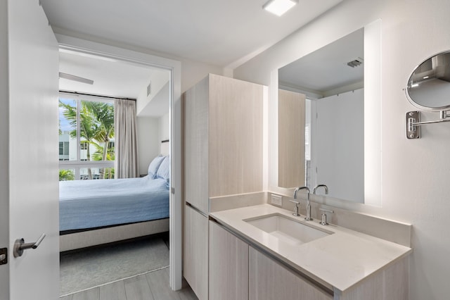 ensuite bathroom featuring vanity, visible vents, wood finished floors, and ensuite bathroom