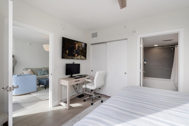 bedroom featuring connected bathroom, a closet, visible vents, and wood finished floors