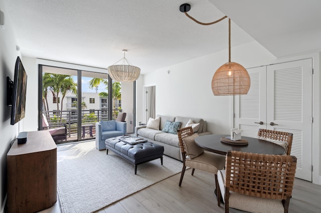 living area featuring light wood-style floors, a wall of windows, and a textured ceiling