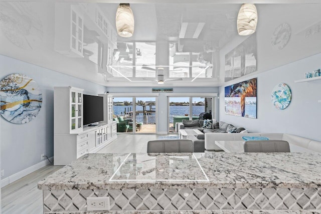 living room with light wood-style floors, a high ceiling, baseboards, and a ceiling fan