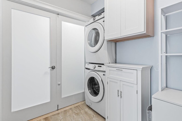 laundry room featuring cabinet space, light wood finished floors, and stacked washer and clothes dryer