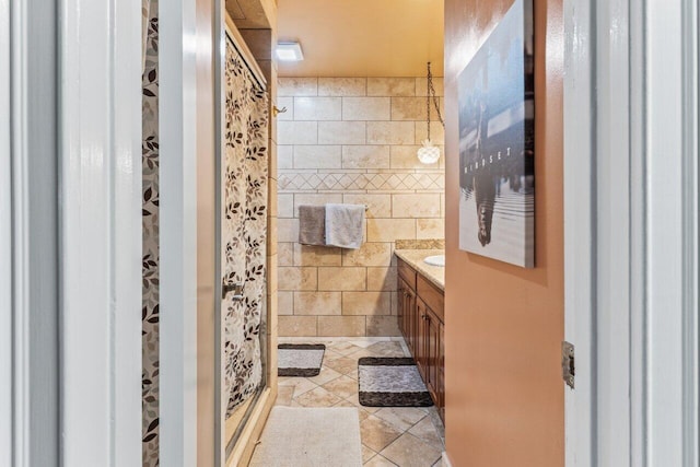 full bath with tile patterned flooring, a shower stall, tile walls, and vanity