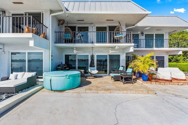 back of house featuring a patio, a balcony, metal roof, outdoor lounge area, and stucco siding