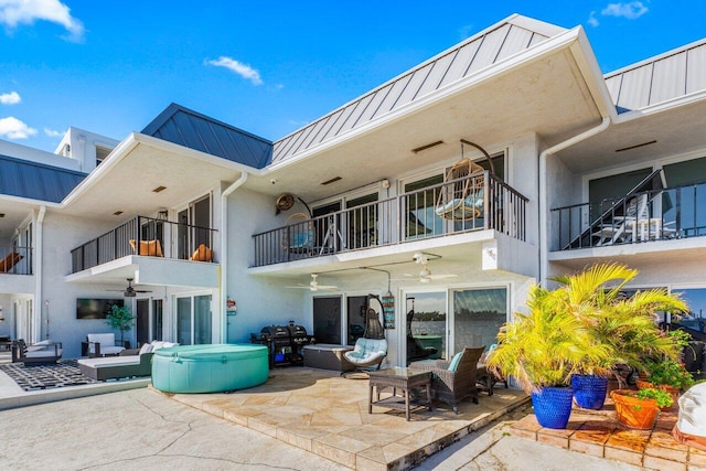 rear view of house featuring ceiling fan, a patio, a standing seam roof, and metal roof