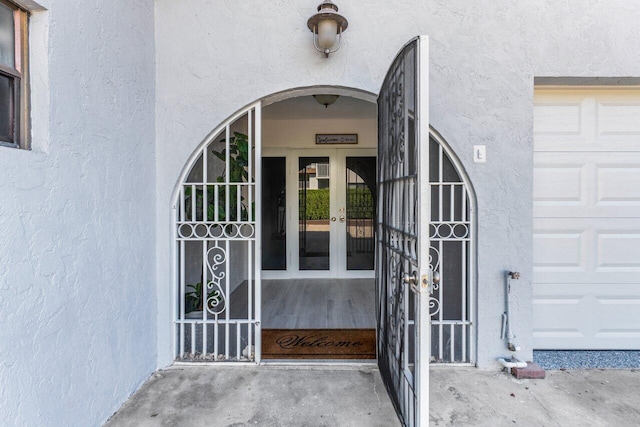 view of exterior entry with a garage and stucco siding