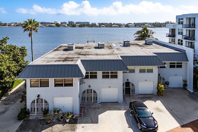 view of front of house featuring an attached garage, driveway, a water view, and stucco siding