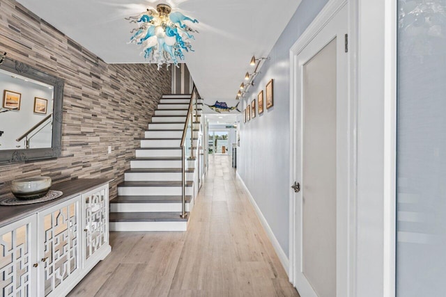 corridor with light wood-style flooring, baseboards, and stairs