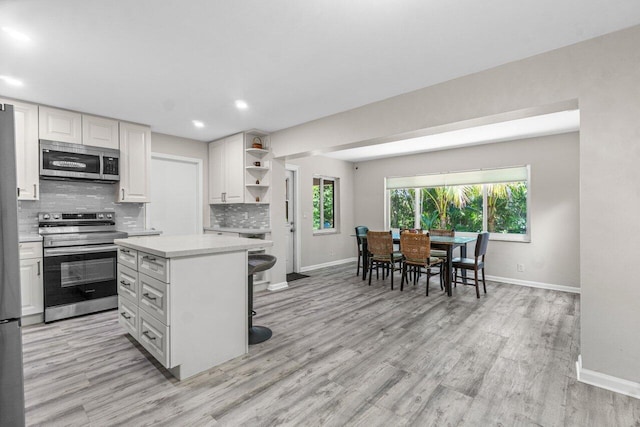 kitchen with a center island, stainless steel appliances, light countertops, white cabinetry, and open shelves