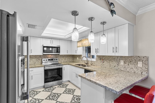 kitchen with pendant lighting, stainless steel appliances, white cabinetry, a sink, and a peninsula