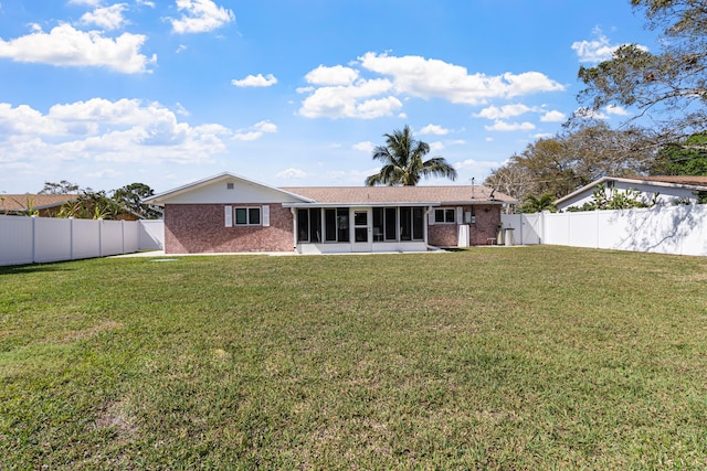 back of house with a sunroom, a fenced backyard, a yard, and brick siding