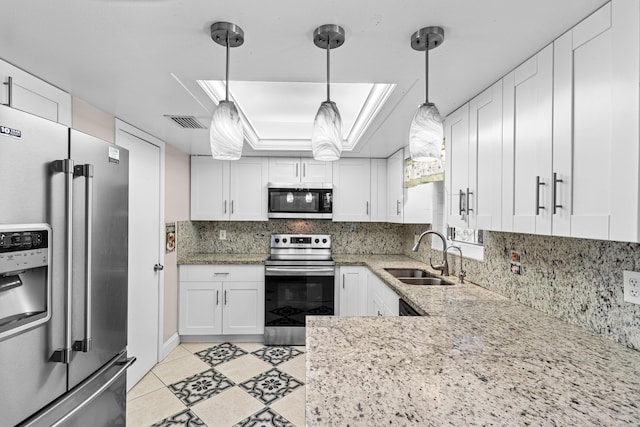 kitchen featuring hanging light fixtures, a tray ceiling, stainless steel appliances, white cabinetry, and a sink